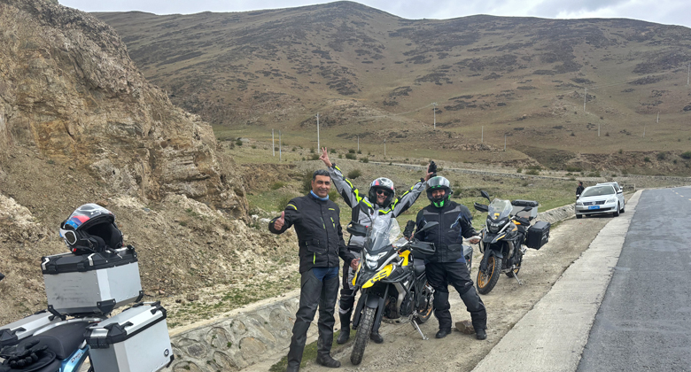 Motorradreisende auf einer Stra&szlig;e in Tibet mit Begleitfahrzeug