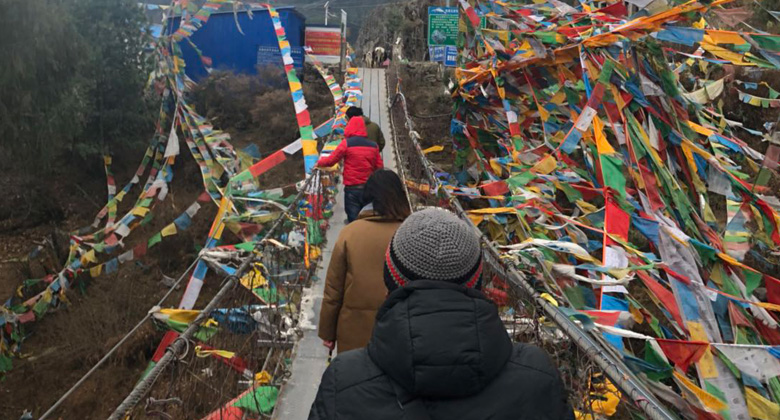 Über die Hängebrücke mit den bunten tibetischen Gebetsfahnen in der Kyipu-Schlucht gehen