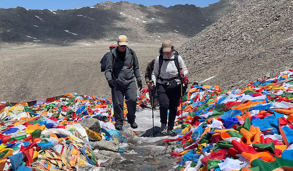 Reisende beim Trekking am Mount Kailash zwischen tibetischen Gebetsfahnen